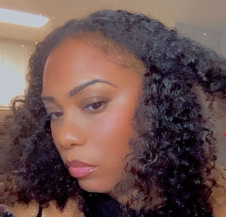 Woman with curly hair wearing a black t-shirt with text, indoors.